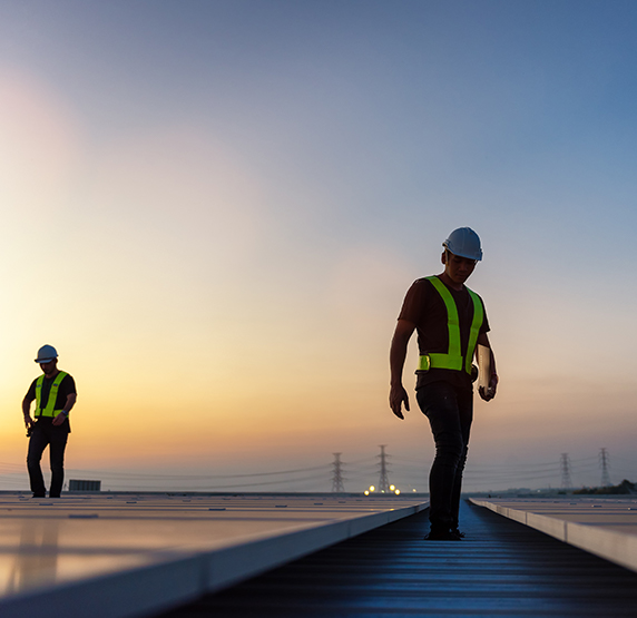 Two men walking through roof-top solar panels at dawn